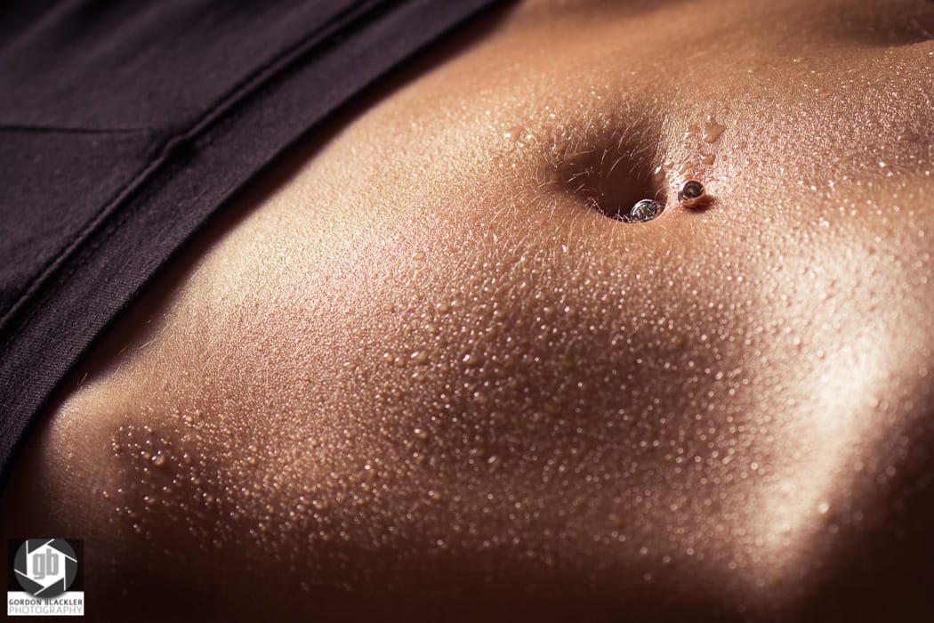 wet skin close-up of woman's stomach and belly button piercing