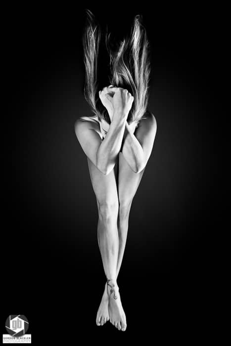fine art implied nude, black and white, low key, woman with arms and legs crossed